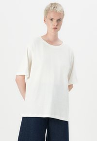 Hvid bomulds t-shirt med en afslappet pasform, rund halsudskæring, korte ærmer og en glat tekstur, parret med mørke denimbukser.