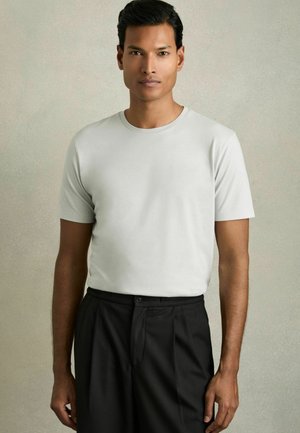 Tricou scurt cu mânecă scurtă, de culoare gri deschis, confecționat dintr-un material moale, asortat cu pantaloni negri ce au sistem de închidere cu nasture și față plisată.