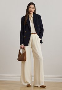 Ναυτικό μπλέ διπλό έμπλαστρο σακάκι, κρεμ πουκάμισο με κουμπιά, κρεμ παντελόνια φαρδιάς γραμμής, καφέ ζώνη, καφέ τσάντα χειρός και ταμπά μυτερές γόβες.