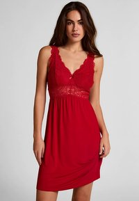 Camisola rossa con rifiniture in pizzo e scollo a V, con gonna fluente e tessuto morbido. Vestibilità aderente con delicati dettagli.