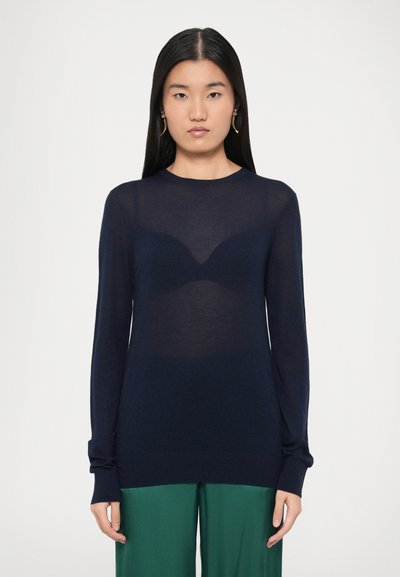 Pull en maille marine transparente avec manches longues, encolure ronde et poignets côtelés. L'apparence superposée met en valeur les détails de la forme sous-jacente.