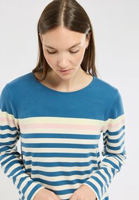 Chemise à manches longues rayée en bleu, avec des rayures horizontales crème, rose pâle et marine. Texture douce avec un col rond.