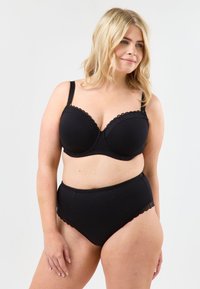 Svart underklädesset bestående av en formad behå med scallopade kanter och höga trosor. Mjuk tygkvalitet med en slät textur och inga synliga mönster.