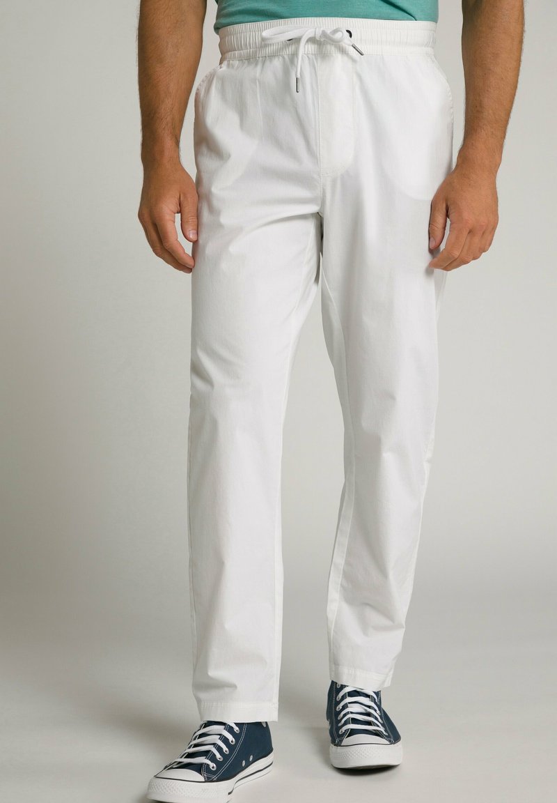 Witte lichte broek met een elastische tailleband en trekkoord. Gekoppeld met marineblauwe sneakers. Soepele textuur en relaxte pasvorm.