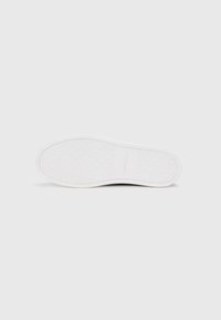 Talpa de sneaker albă cu un model texturat și numele mărcii embosat. Talpa este rotunjită, având un design neted și un material flexibil.