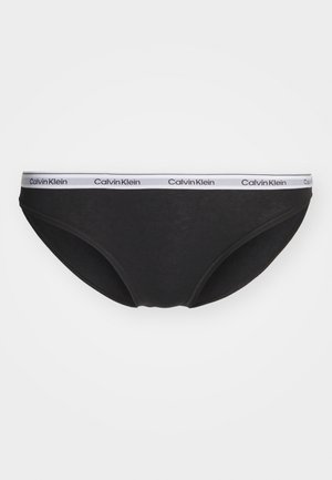 Črne hlačke z mehkimi vlakni in elastičnim pasom, na katerem je bel logotip "Calvin Klein". Preprosta zasnova brez dodatnih okraskov.