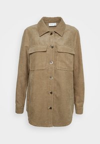 Tan kordjacka i lätt ribbat tyg med krage, framknäppning, två bröstfickor och långa ärmar. Strukturerad tyg med vertikala ribbor.