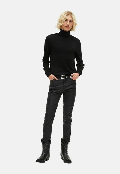 Suéter negro de cuello alto combinado con pantalones de cuero negro ajustados y botas de vaquero negras; textura suave, diseño esbelto y detalles sutiles.