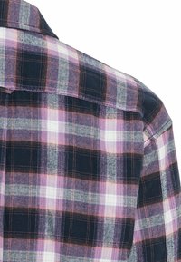 Vue arrière d'une chemise à carreaux aux couleurs marine, rose, blanc et gris, avec un col plié sur fond blanc.