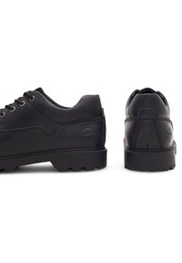 Čierne kožené topánky s nízkym profilom, okrúhlou špičkou a robustnou gumovou podrážkou s viditeľným dezénom, doplnené minimálnymi švovými detailmi.