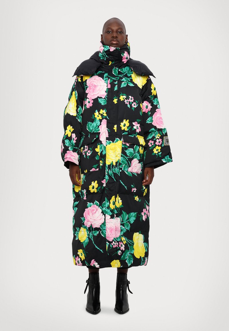 Abrigo acolchado de tela negra con gran estampado floral en rosa y amarillo. Cuenta con cuello alto, mangas largas y dos bolsillos frontales.
