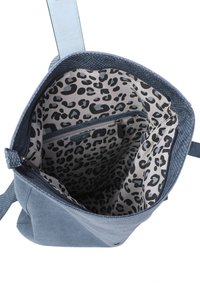 Niebieska torba na ramię z płóciennego materiału o teksturowanym wykończeniu oraz z brązowymi skórzanymi akcentami. Wnętrze ozdobione jest podszewką w cętki i posiada kieszeń z zamkiem błyskawicznym.