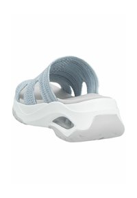 Ljusblåa slip-on sandaler med strukturerade stickade remmar och en vit dämpad sula. Har en lätt upphöjning vid hälområdet.