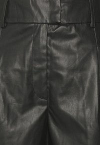 Pantalon en cuir noir avec une texture lisse, une taille haute et des poches latérales ornées de détails de coutures discrètes.