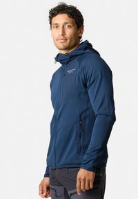 Marineblauwe, ritssluitende hoodie-jack met textuurstof en een aangesloten ontwerp. Beschikt over zij-rits zakken en een logo op de borst.