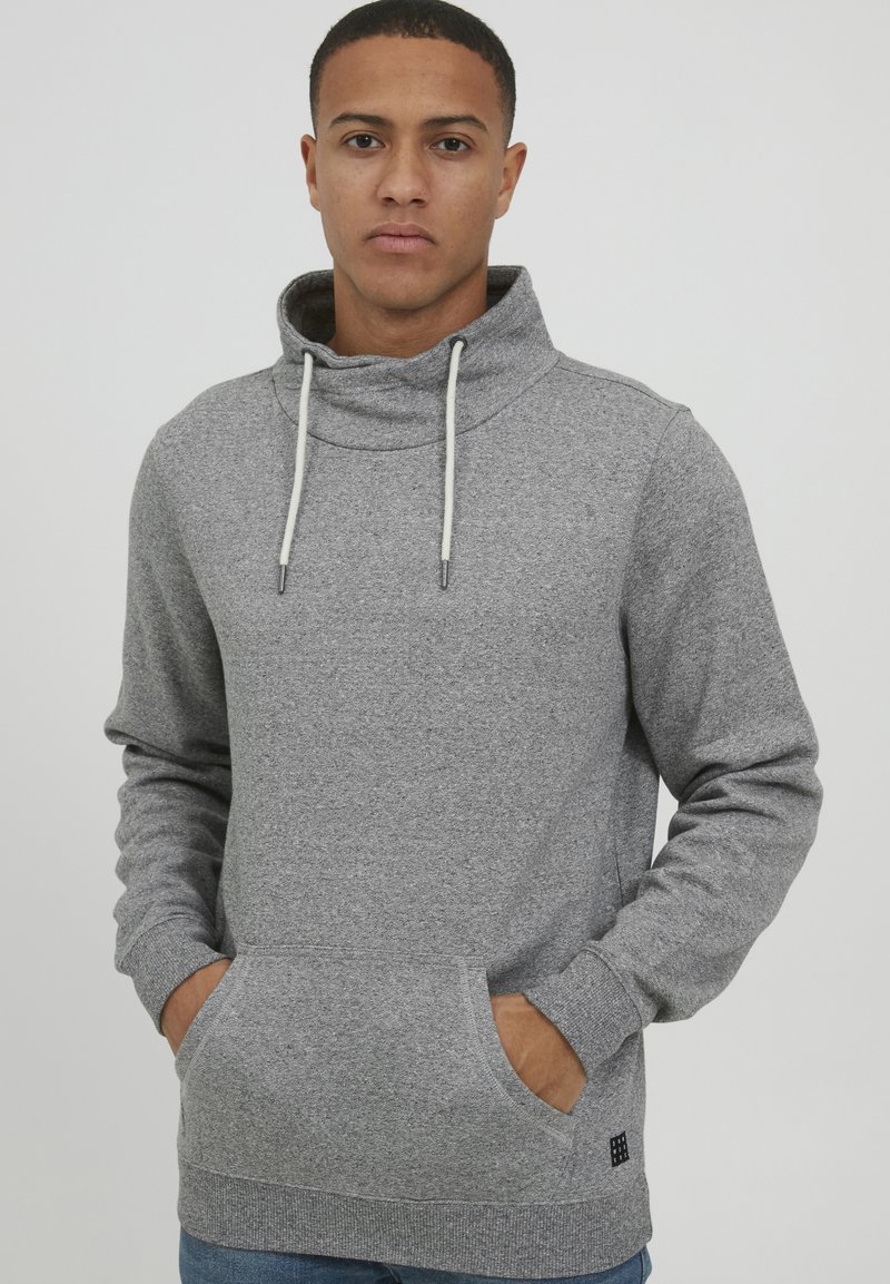 Grijze hoodie gemaakt van een zacht materiaal, met een hoge kraag, trekkoorden en een frontzak. Getextureerde stof met een ribbelzoom.