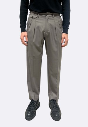 Pantaloni grigio chiaro plissettati con una vestibilità comoda, dotati di passanti per cintura e due tasche laterali, abbinati a scarpe nere stringate.