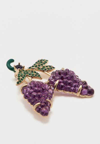 Χρυσό κονκάρδα σε σχήμα δύο μοβ σταφυλιών με φύλλα από πράσινες πολύτιμες πέτρες και σκούρο πράσινο κυρτό μίσχο, σε λευκό φόντο.