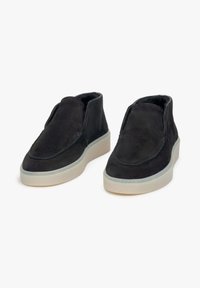 Czarne zamszowe pantofle slip-on z zaokrąglonym czubkiem i wyściełanym kołnierzem. Posiadają kontrastującą białą gumową podeszwę oraz minimalne detale szewne.