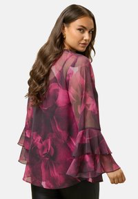 Blusa trasparente con maniche a campana a strati in una gradazione di rosa intenso e borgogna con motivo floreale. Tessuto leggero con una texture morbida.