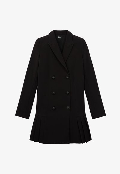 Cappotto doppiopetto nero realizzato in tessuto strutturato, caratterizzato da un colletto a revers, sei bottoni texture e dettagli plissettati all'orlo.