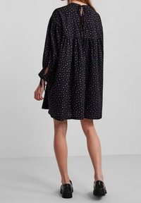 Černé šaty s barevnými puntíky, volný střih, dlouhé rukávy se šňůrkami, nabíraný pas, uzavírání na klíčovou dírku na zádech a délka ke kolenům.