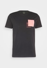 T-shirt en coton noir à manches courtes, avec un design de poche texturée rose et des lignes horizontales sur le côté gauche de la poitrine.