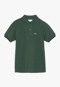 Grön pikétröja i bomull, med klassisk krage, två knappar och en liten broderad logotyp på vänster bröst.