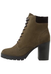 Olijfgroene suède enkellaars met een stevige zwarte hak, vetersluiting en versterkte neus. Voorzien van een glad oppervlak en contrasterende zwarte accenten.