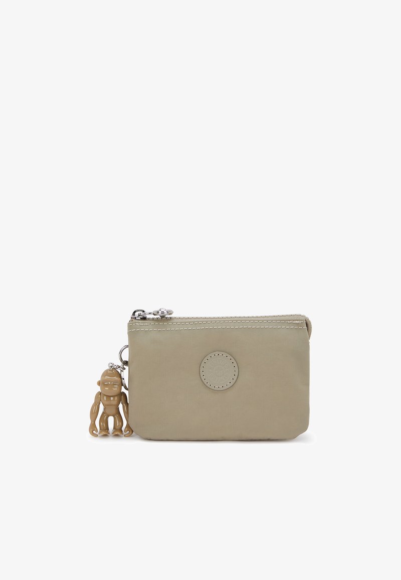 Beige nylon pouch with a circular logo, zip closure, and a tan rubber octopus charm attached. Smooth texture and simple design.