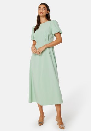 Robe maxi vert menthe avec des manches bouffantes, corsage ajusté et jupe fluide. Texture lisse, design minimaliste, et sans motifs ou accessoires visibles.