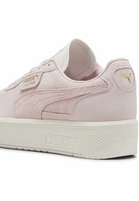 Puma Palermo sneakers in zachtroze suede. Voorzien van een witte rubberen zool en gouden logo-accenten. Glide en textuur overlays op de bovenkant.