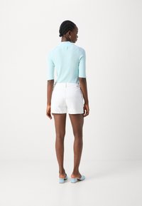 Light blue, ribbed knit polo shirt with a collar; white shorts; light blue block-heeled sandals; smooth textures and fitted silhouette.