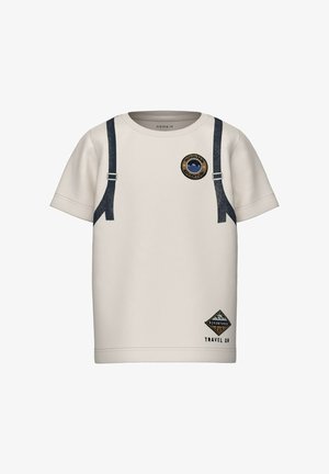 Maglietta beige chiaro con bretelle blu navy stampate sul davanti, toppa rotonda con disegno di montagna e distintivo triangolare con la scritta "TRAVEL ON."