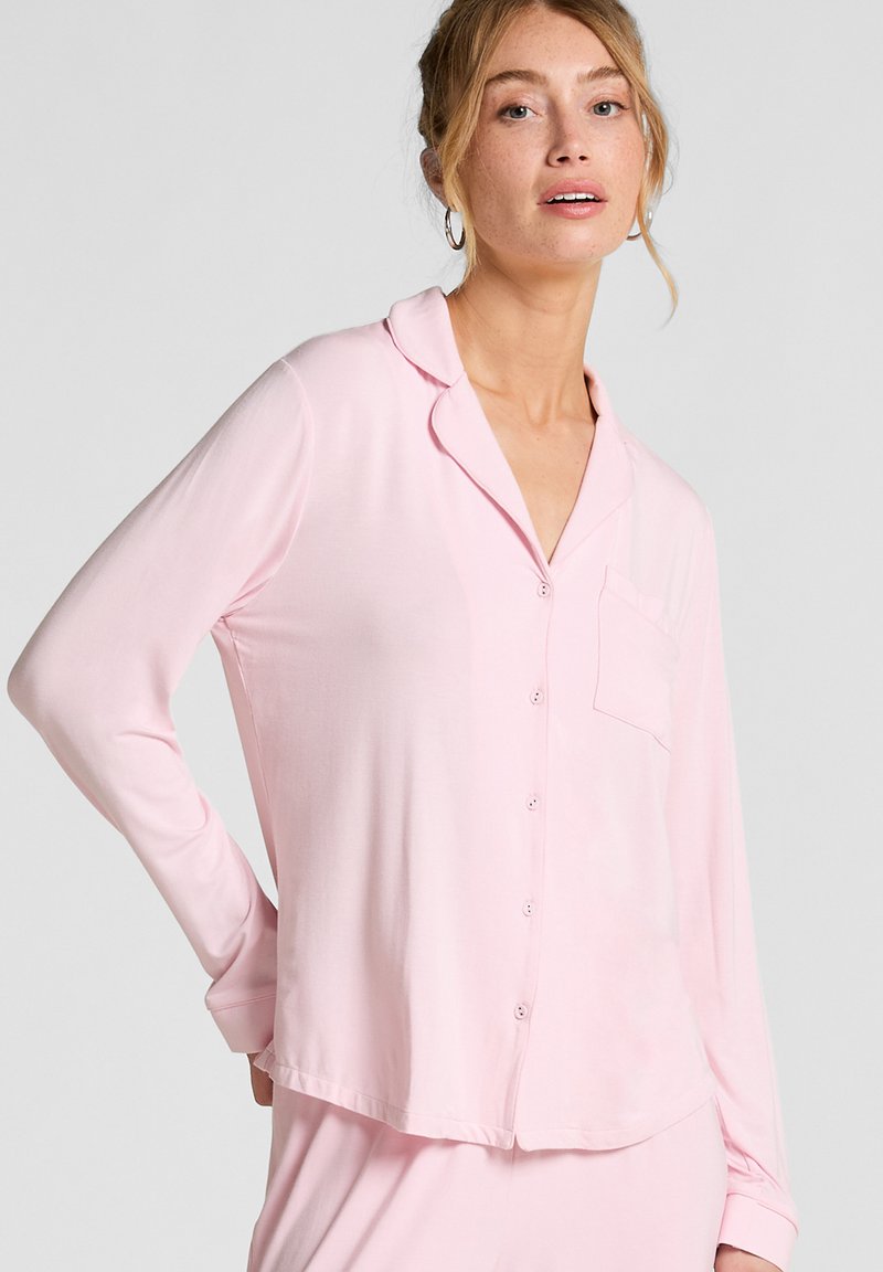 Lichtroze lange mouwen pyjama top met een notch-kraag, een voorzak en knoopsluiting, gemaakt van zachte, gladde stof.