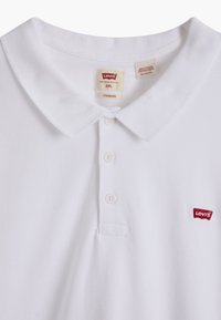 Polo blanc Levi's avec patte de boutonnage à trois boutons, col classique et écusson rouge du logo Levi's sur la poitrine, taille 2XL.