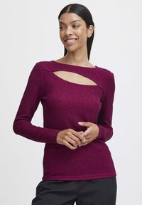 Burgundy pitkähihaan paita, jossa on leikkauksellinen kaula-aukko design. Valmistettu teksturoidusta materiaalista, jossa on istuva siluetti. Sujuva kankaan pinta.