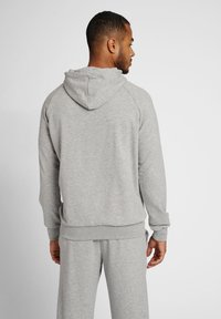 Grijze hoodie met raglanmouwen, geribbelde manchetten en zoom. Zacht, textuurachtig materiaal, zichtbare naden en een relaxte pasvorm.