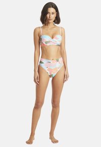 Ensemble de bikini deux pièces avec des motifs floraux multicolores. Le haut présente un design tordu ; le bas taille haute offre une couverture modérée.