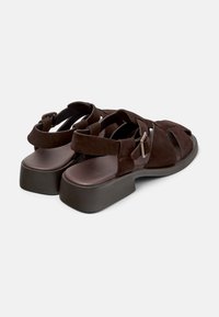 Sandalias de ante marrón con tiras cruzadas, puntera abierta, plantilla acolchada y tacón de plataforma grueso. Incluye cierre ajustable con hebilla.