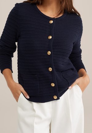 Cardigan en maille marine avec une finition texturée, col rond, six boutons dorés et deux poches avant.