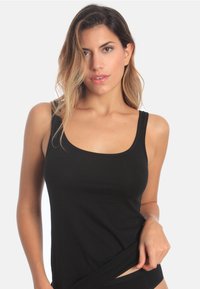 Black cotton tank top with a scoop neckline and wide straps. Fitted design that highlights the torso, smooth texture with no visible patterns.