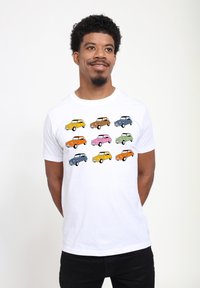 Hvid T-shirt med et mønster af otte tegneserie-biler i forskellige farver: gul, orange, brun, pink, blå og grøn. Simpelt design.