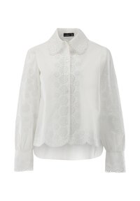 White blouse featuring a scalloped hem, button front, and intricate floral embroidery on sleeves and body. Long sleeves with button cuffs.