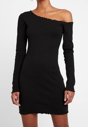 Vestido de punto negro acanalado con mangas largas y escote asimétrico, un hombro descubierto y borde y puños con acabado ondulado.