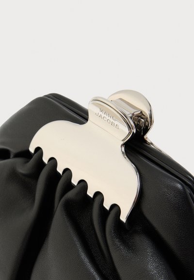 Μαύρο δερμάτινο τσαντάκι χειρός με ασημένιο μεταλλικό κούμπωμα που έχει κυματιστό σχέδιο. Υφασμάτινη υφή με ρίγες προσθέτει λεπτομέρεια. Συμπαγές σχήμα.