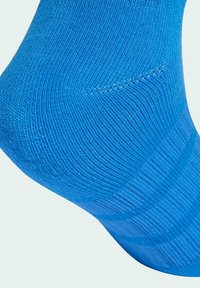 Krupni plan plave pletene čarape, s naglaskom na detaljnu rebrastu teksturu i pojačane šavove.