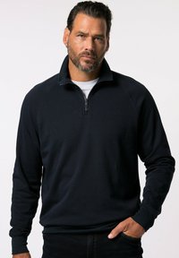 Pullover a collo alto blu scuro con zip a un quarto realizzato in tessuto morbido. Presenta un colletto e polsini a coste, con un logo discreto ricamato sul petto.