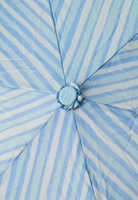 Tissu rayé bleu et blanc avec un motif matelassé, présentant un bouton central bleu clair et des sections triangulaires distinctes rayonnant vers l'extérieur.