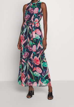 Maximekko tummansinisellä värillä, jossa on vaaleanpunaisia ja vihreitä kukkakuoseja. Tässä mekossa on muotopohja, vyötärölle sidottu vyö ja kevyttä kangasta.